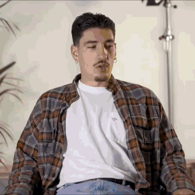 a man wearing a plaid shirt and a white t-shirt is smoking a cigar