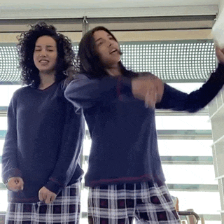 two women in pajamas are dancing in front of a window