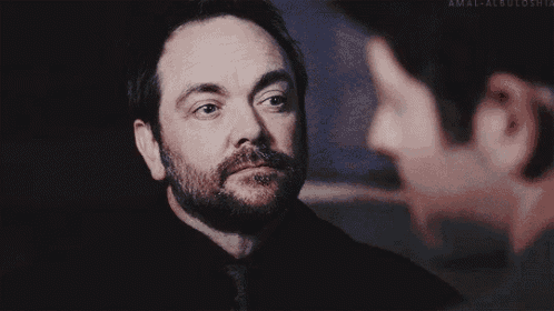 a man with a beard is standing next to another man in a dark room .
