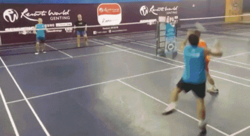 people playing badminton on a court with remote world written on the wall behind them