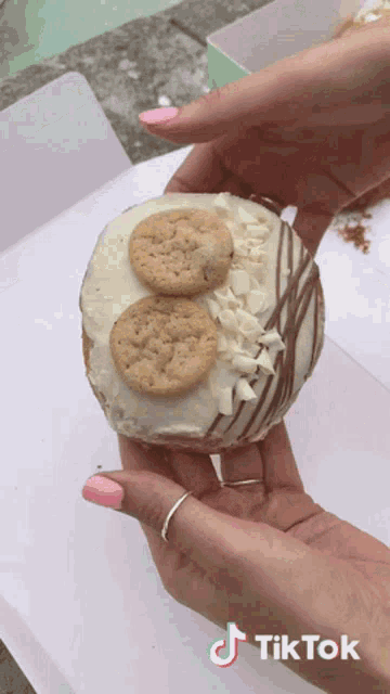 a person holding a cookie doughnut with a tiktok logo on the bottom