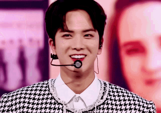a close up of a man wearing a microphone and a houndstooth jacket