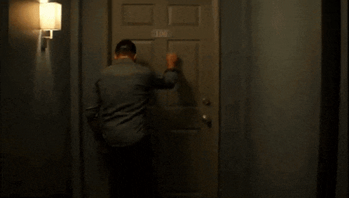 a man is knocking on a door in a hallway .