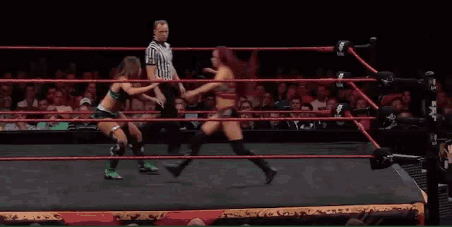 a woman is kicking another woman in the face while a referee watches .