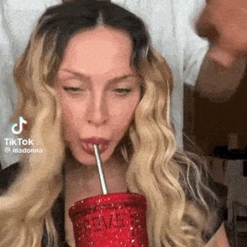 a woman is drinking a drink through a straw from a red cup .