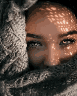 a close up of a woman 's face with a scarf around her neck covering half of her face .
