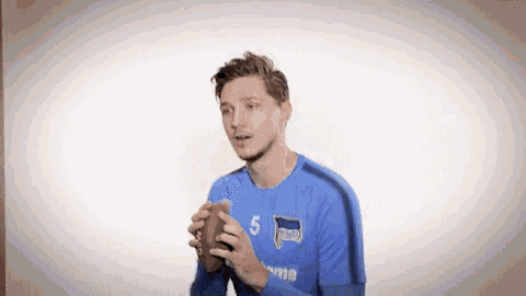 a man in a blue shirt is holding a football in his hands .