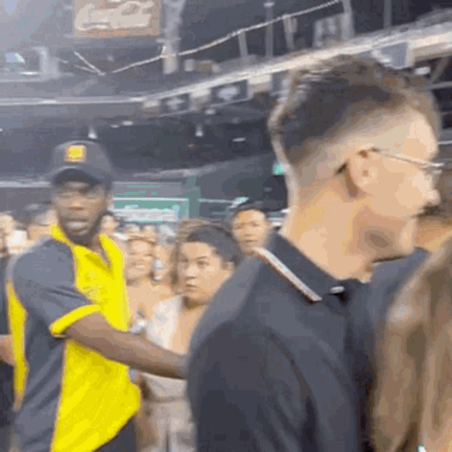 a man in a yellow shirt is talking to a man in a black shirt .