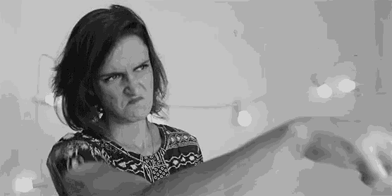 a woman is making a funny face in a black and white photo while holding her hand up .