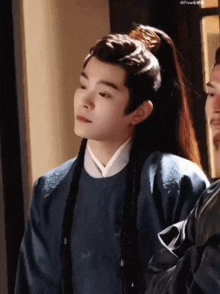 a young man with long hair is wearing a ponytail and a traditional costume .