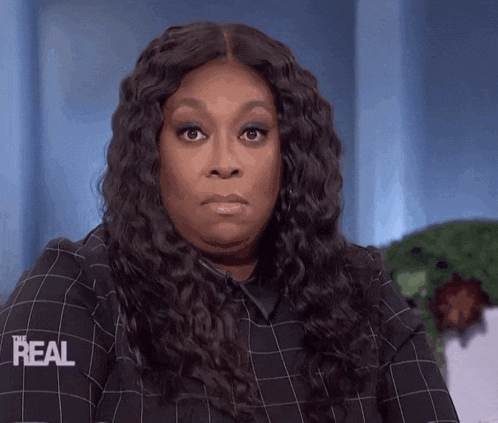 a woman wearing a plaid shirt that says real on the sleeve