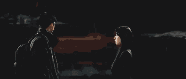 a woman in a suit and white shirt is standing in front of a man .