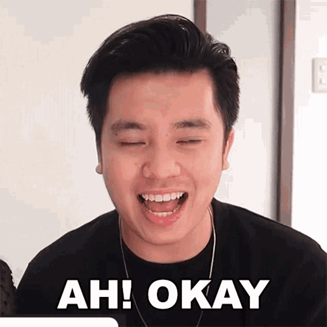 a man is making a funny face with his eyes closed and the words `` ah ! okay '' written on his face .