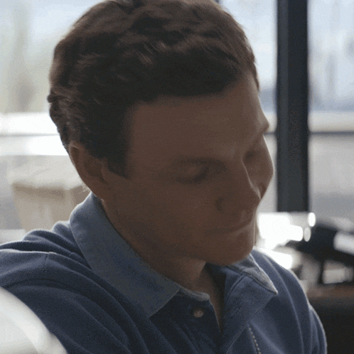 a man in a blue shirt looks down at something