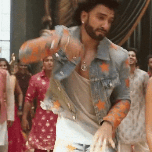 a man with a beard wearing a denim jacket is dancing in front of a crowd .