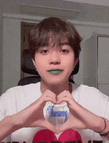 a young man with green lipstick making a heart shape