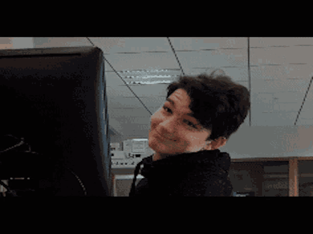 a young man is looking at a computer screen and making a funny face