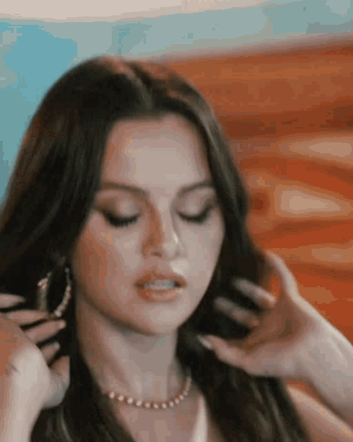 selena gomez is wearing hoop earrings and a necklace .