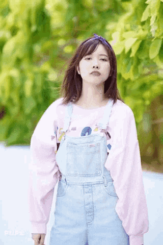 a girl wearing overalls and a pink sweater with the word pure on it