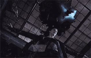 a woman is laying on the floor in a dark room with a blue light coming from the ceiling .