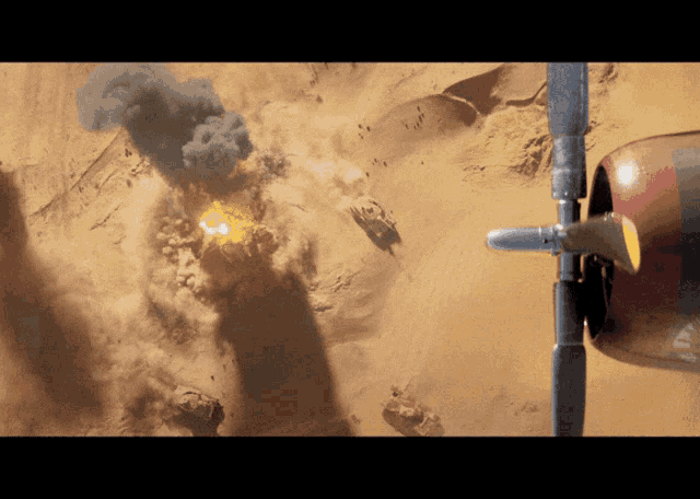 a plane is flying over a desert with smoke coming out of the ground