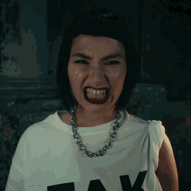 a woman wearing a white t-shirt with the letter k on it is making a funny face