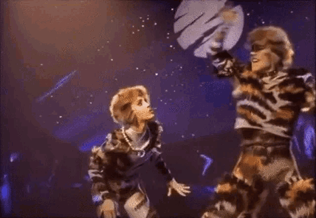 two tigers are dancing on a stage in front of a planet .