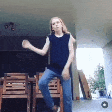 a young girl is dancing in front of a table and chairs .