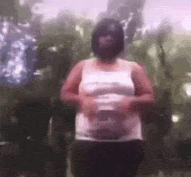 a blurry picture of a woman in a white tank top holding her belly