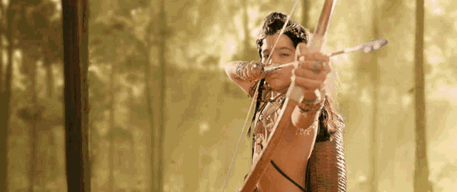a woman is holding a bow and arrow in her hand