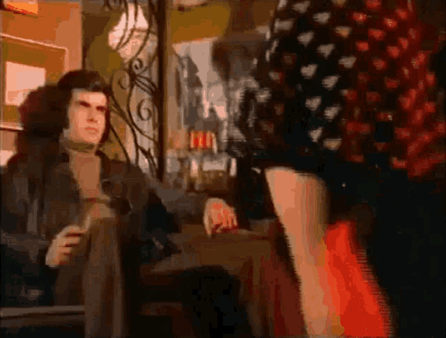 a man is sitting in a chair with a glass of wine and a woman is standing in front of him