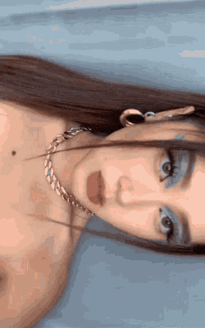 a close up of a woman 's face with a necklace around her neck