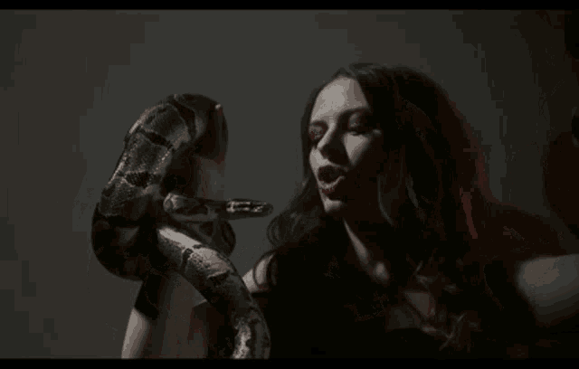 a woman is holding a snake around her neck and screaming .