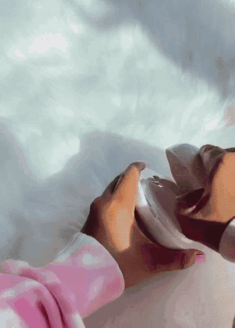a person wearing a pink polka dot pajama is holding a white object