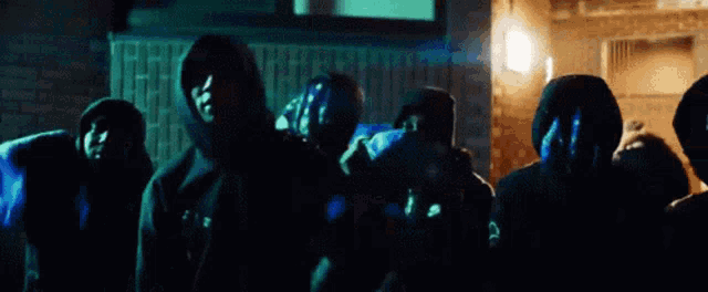 a group of people wearing masks and hoods are standing in front of a building .