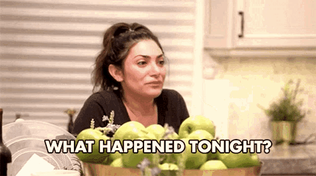 a woman is sitting at a table with a bowl of apples and says what happened tonight .