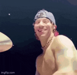 a shirtless man is playing drums and smiling while wearing a hat .