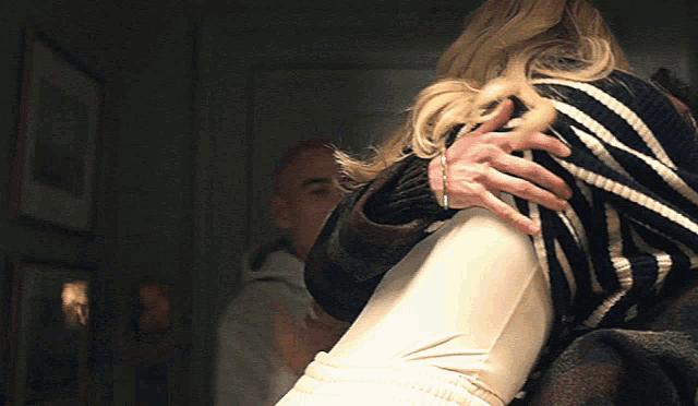 a woman in a striped sweater is being held by a man