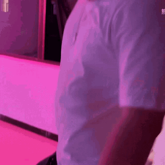 a man in a white shirt is standing in front of a purple wall