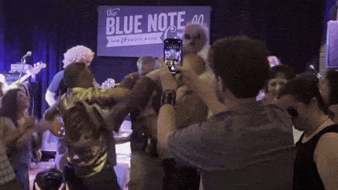 a man taking a picture of a group of people in front of a sign that says the blue note