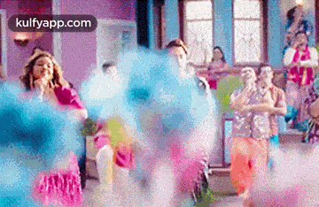 a group of people are dancing in a room with blue powder coming out of the air .