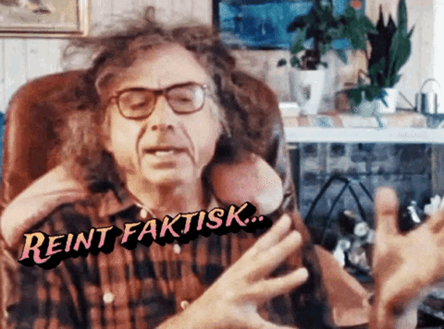 a man with curly hair and glasses is sitting in a chair with the words beint faktisk written above him