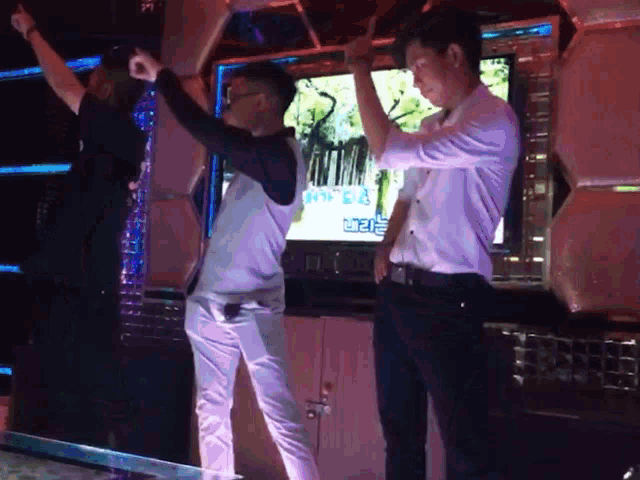 a man in a white shirt is dancing in front of a tv screen that says ' a ' on it