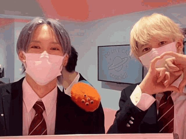 two people wearing face masks in front of a sign that says go live cafe cosmi