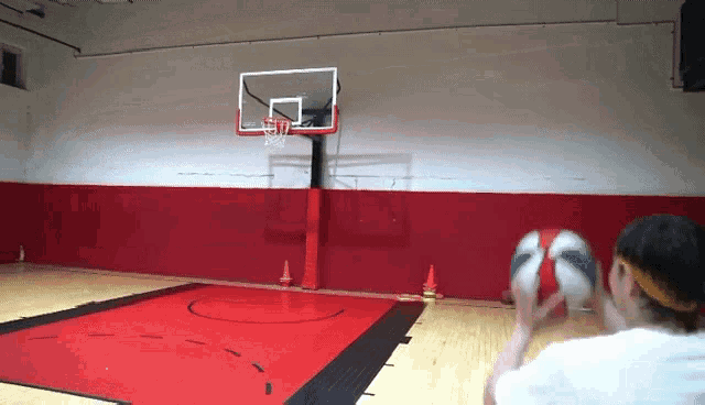 a person is playing basketball in a gym with a basketball hoop