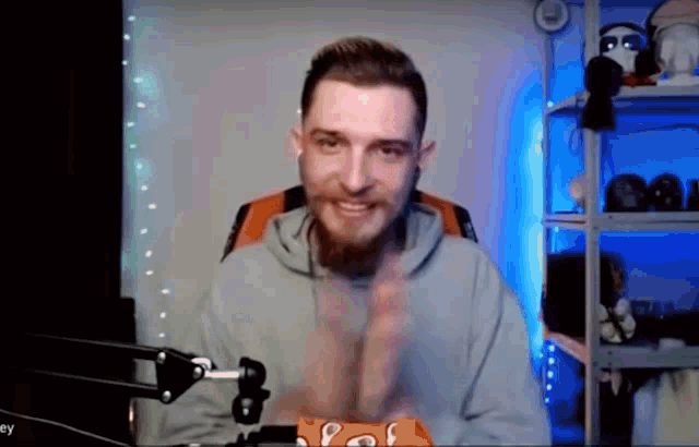 a man with a beard is sitting in front of a microphone and waving his hands .