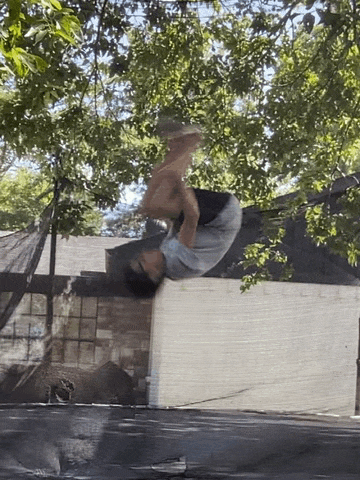 a man is doing a flip on a trampoline in front of a house .