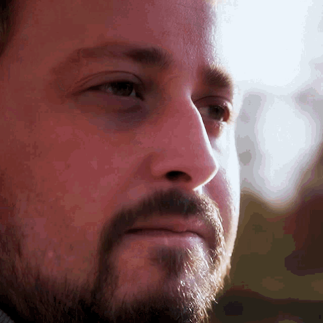 a man with a beard looks at the camera with a serious look on his face