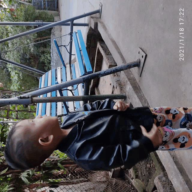 a little boy is standing in front of a blue bench with the date of 2021/11/03 17:22