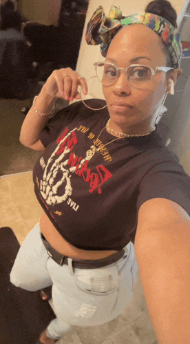 a woman taking a selfie wearing a crop top that says ' skeleton hand ' on it